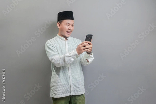 Fototapeta Happy asian muslim man using smart phone cellphone for calls