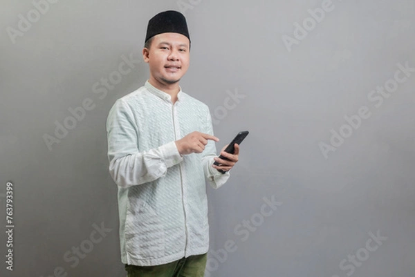 Fototapeta Happy asian muslim man using smart phone cellphone for calls