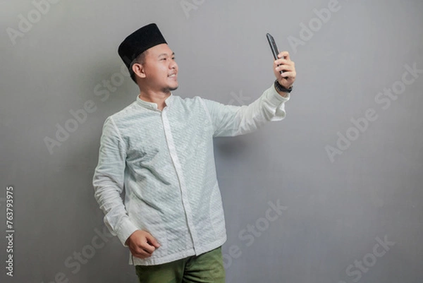 Fototapeta Happy asian muslim man using smart phone cellphone for calls