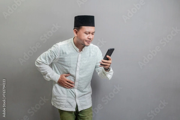 Fototapeta Asian Muslim man holding back hunger and waiting for the time to break the fast