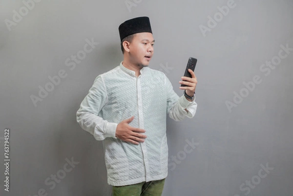 Fototapeta Asian Muslim man holding back hunger and waiting for the time to break the fast