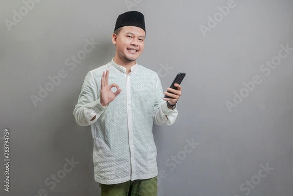 Fototapeta Asian Muslim man standing with crossed arm isolated on a gray background