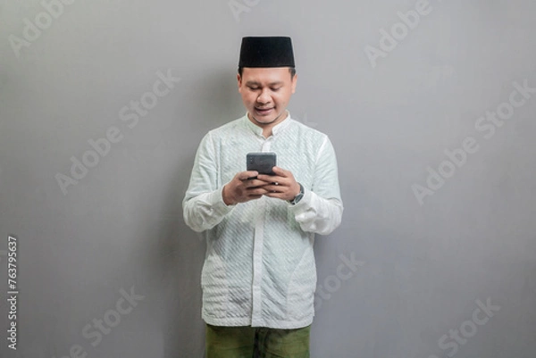Fototapeta Happy asian muslim man using smart phone cellphone for calls