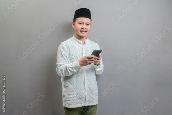 Fototapeta Happy asian muslim man using smart phone cellphone for calls