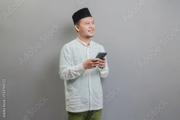 Fototapeta Happy asian muslim man using smart phone cellphone for calls