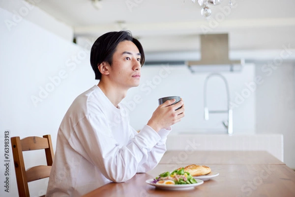 Fototapeta リビングにて朝食を食べる若い日本人の男性