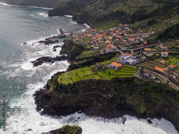 Fototapeta Aerial view of Seixal, a little village by the ocean with waves and surrounded with incredible mountains on the island of Madeira, Portugal.