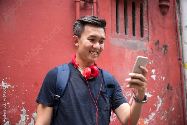 Obraz Cool Asia man using his smart phone.