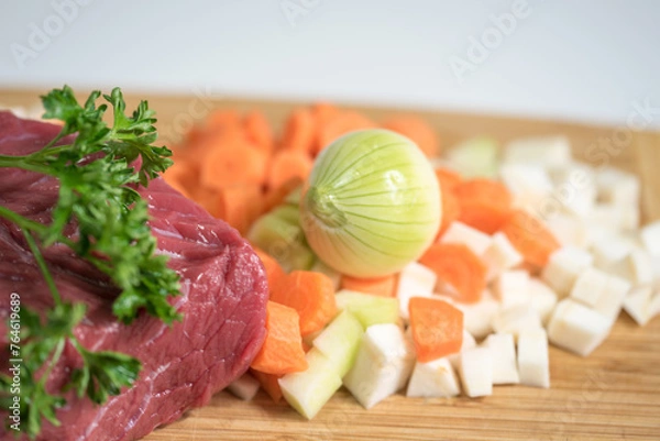 Fototapeta Raw beef meat on a cutting board with fresh vegetable