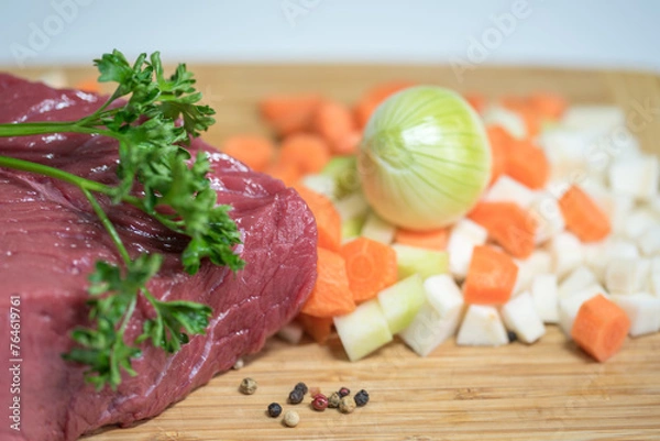 Fototapeta Raw beef meat on a cutting board with fresh vegetable