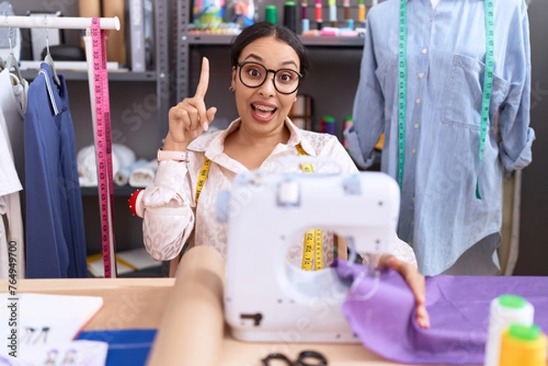 Fototapeta Young arab woman dressmaker designer working at atelier pointing finger up with successful idea. exited and happy. number one.