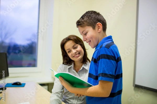 Fototapeta school boy with notebook and teacher in classroom