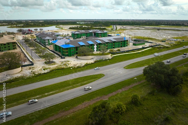 Fototapeta Top view of apartment buildings under construction in developing suburban area near transport infrastructure. Development of residential housing in american suburbs. Real estate market in the USA