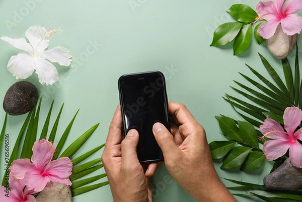 Fototapeta Smartphone with spring flowers on green background. 