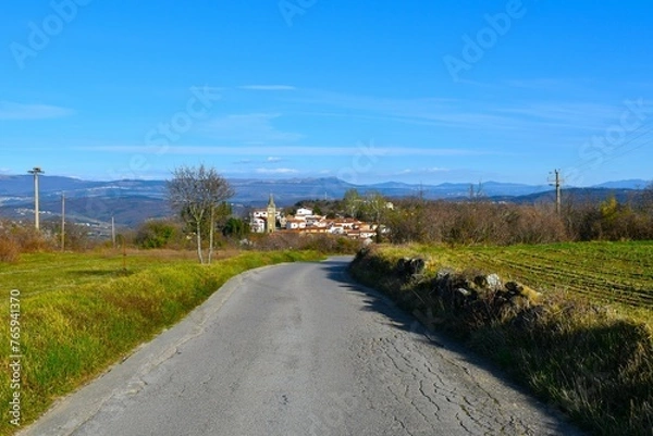 Fototapeta Asphalt road in Istria, Slovenia with Pomjan village and hills in the background
