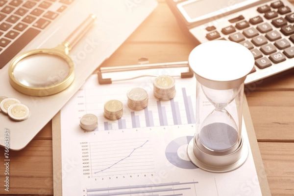 Obraz Coins, hourglasses, laptops, and calculators placed on financial data reports