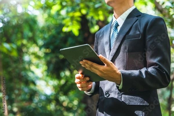Fototapeta Business man using tablet to analyze ESG concept ,Sustainable development goal (SDGs) Ideas Globe Glass energy-based green business can limit climate change and global warming.