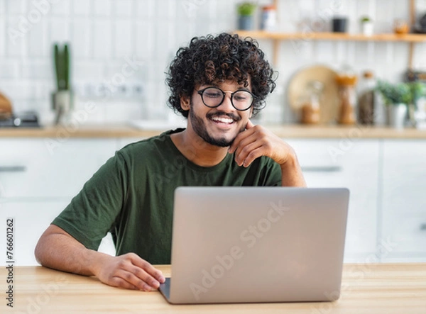 Fototapeta Portrait of successful freelancer or student working on new project. Smiling young indian man using laptop to work remotely from home