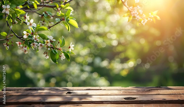 Fototapeta Slightly blurred out of focus wallpaper of tree branches and garden under sunlight from point of view of empty wooden table.