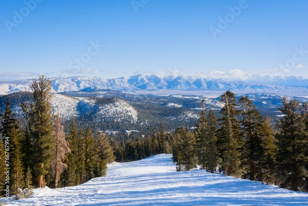 Fototapeta An empty, snowy ski slope with a view of snow-capped mountains in the distance. Mammoth Lakes, California