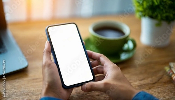 Fototapeta Mobile Phone for Mockup - Mobile Phone held by Hand in an Office or Cafe Environment - Template for Application Presentation