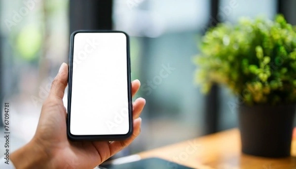 Fototapeta Mobile Phone for Mockup - Mobile Phone held by Hand in an Office or Cafe Environment - Template for Application Presentation