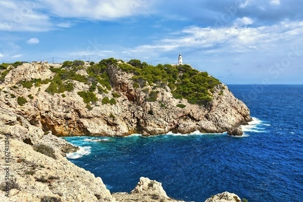 Fototapeta A sea with waves hitting the rocky shore and blue summer skies