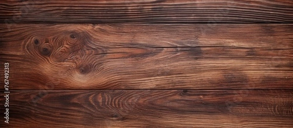 Fototapeta A closeup shot of a brown wooden table showcasing the intricate wood grain pattern. The table is made of hardwood planks with a glossy varnish finish, giving it a sleek and elegant look