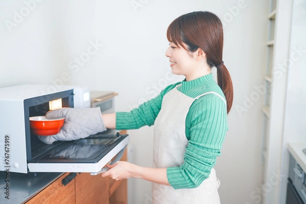 Obraz オーブンレンジを使って料理をする女性