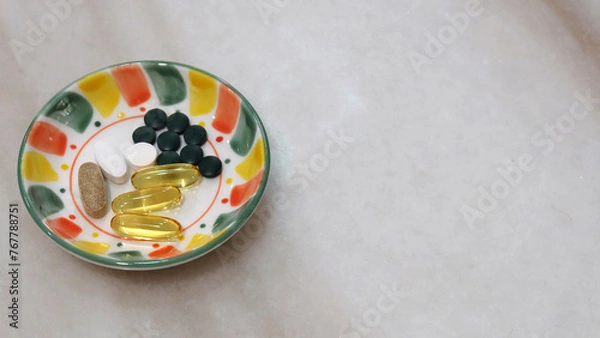 Obraz A small plate with various health supplement pills and capsules. On a marble surface, with copy space on the right.