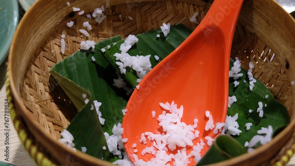 Obraz An empty serving basket with banana leaf and some leftover cooked white rice, with an orange rice ladle.