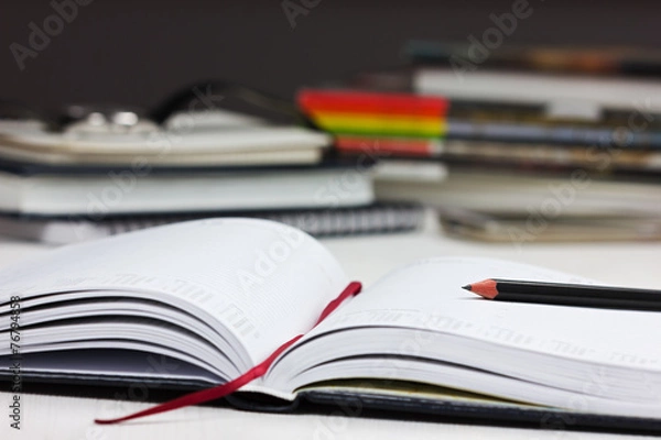 Fototapeta workplace with open a business diary and pencil.