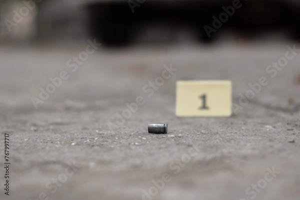 Fototapeta Pistol bullet shell on cement floor with blurred number one yellow paper background, concept for investigation and crime by using gun, soft focus.