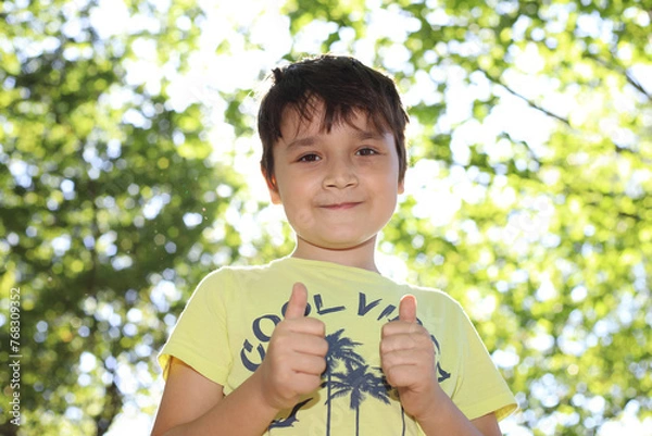 Fototapeta Niño sonriente con un fondo de hojas desenfocadas
