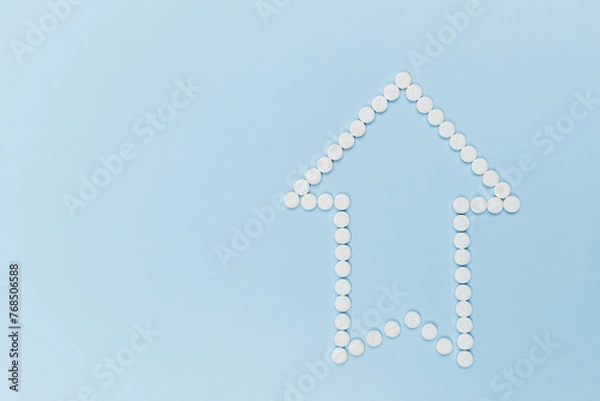 Obraz an arrow pointing to the top, made of identical white tablets on a blue background