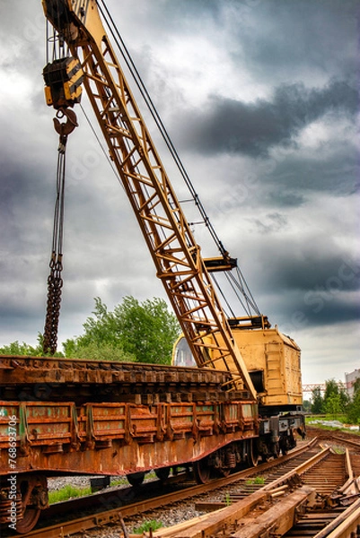 Fototapeta A large crane is standing on top of a railway track, potentially in the process of construction or repair work