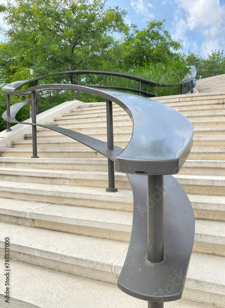 Fototapeta Undulating outdoor metal staircase railing. Stairs in a public park. Concrete stairway in a city.