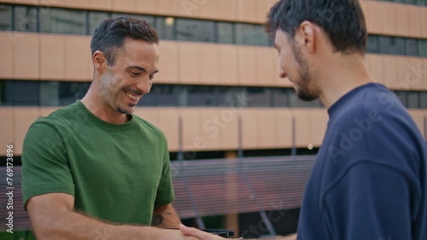 Obraz Cheerful postman delivering box to customer in modern business district closeup