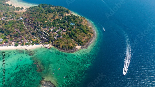 Fototapeta Speedboat tour around Phi Phi islands, Krabi, Thailand. Aerial view of a boat going around a tropical island surrounded by coral reef. 