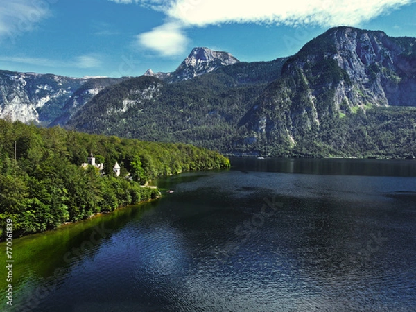 Fototapeta A lake and a mountain with green trees above the lake in the summer and on a beautiful sunny day