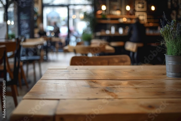 Fototapeta Coworking space with empty wooden table and a cafe area in background
