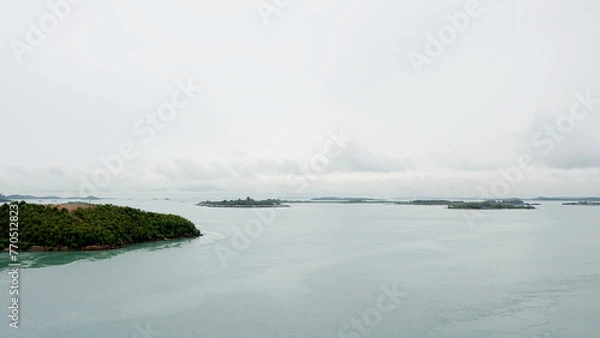 Obraz Groups of small islands stretched into the far horizon, with calm sea and gloomy sky. View from on top of Barelang Bridge, Indonesia.