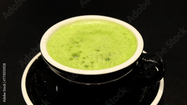 Obraz Closeup of a cup of matcha green tea drink, with some froth on the top. With a black cup and a black background.