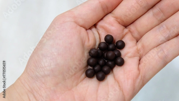 Obraz Palm with a small pile of traditional Chinese medicine in small black balls. 
