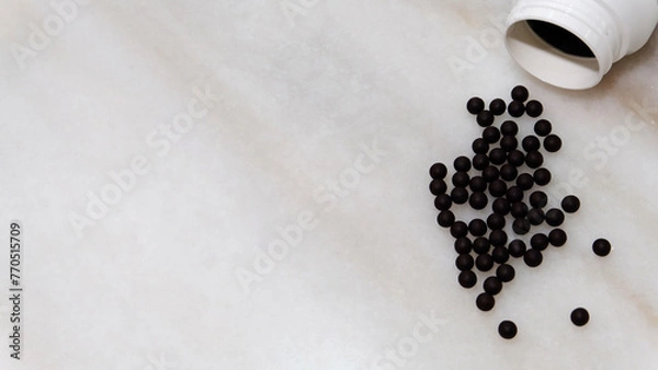 Obraz Traditional form of Chinese medicine in small black balls. On marble surface, with copy space on the left.