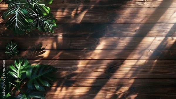 Fototapeta The image is a dark wood background with a few green leaves in the corner. The leaves are casting shadows on the wood.