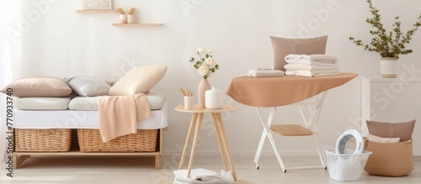 Fototapeta An interior design featuring furniture such as a couch, table, and ironing board in a living room with a window, wood flooring, and chair