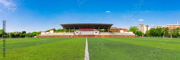 Fototapeta The unmanned outdoor football stadium is located on the university campus, with clear skies