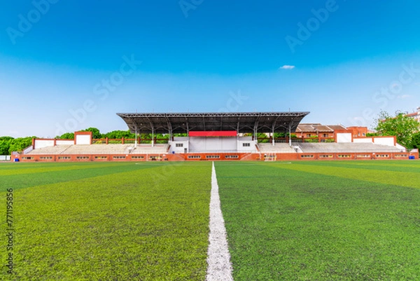 Fototapeta The unmanned outdoor football stadium is located on the university campus, with clear skies