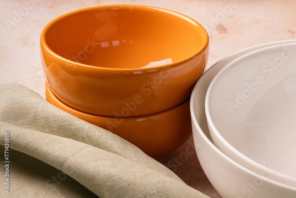 Fototapeta Orange and white bowls on a beige stone tabletop.